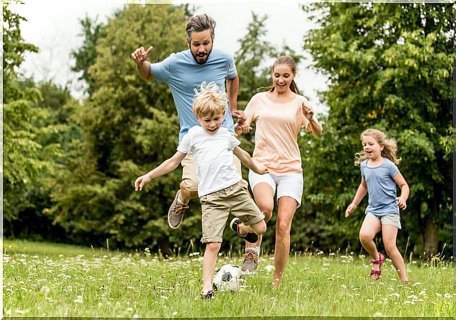 Father and his three children playing with the ball in the garden of their house