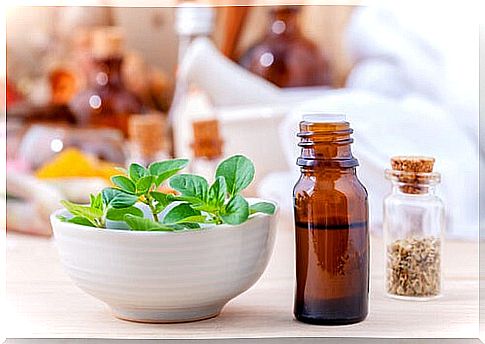 Oil of oregano next to a bowl with leaves of the plant