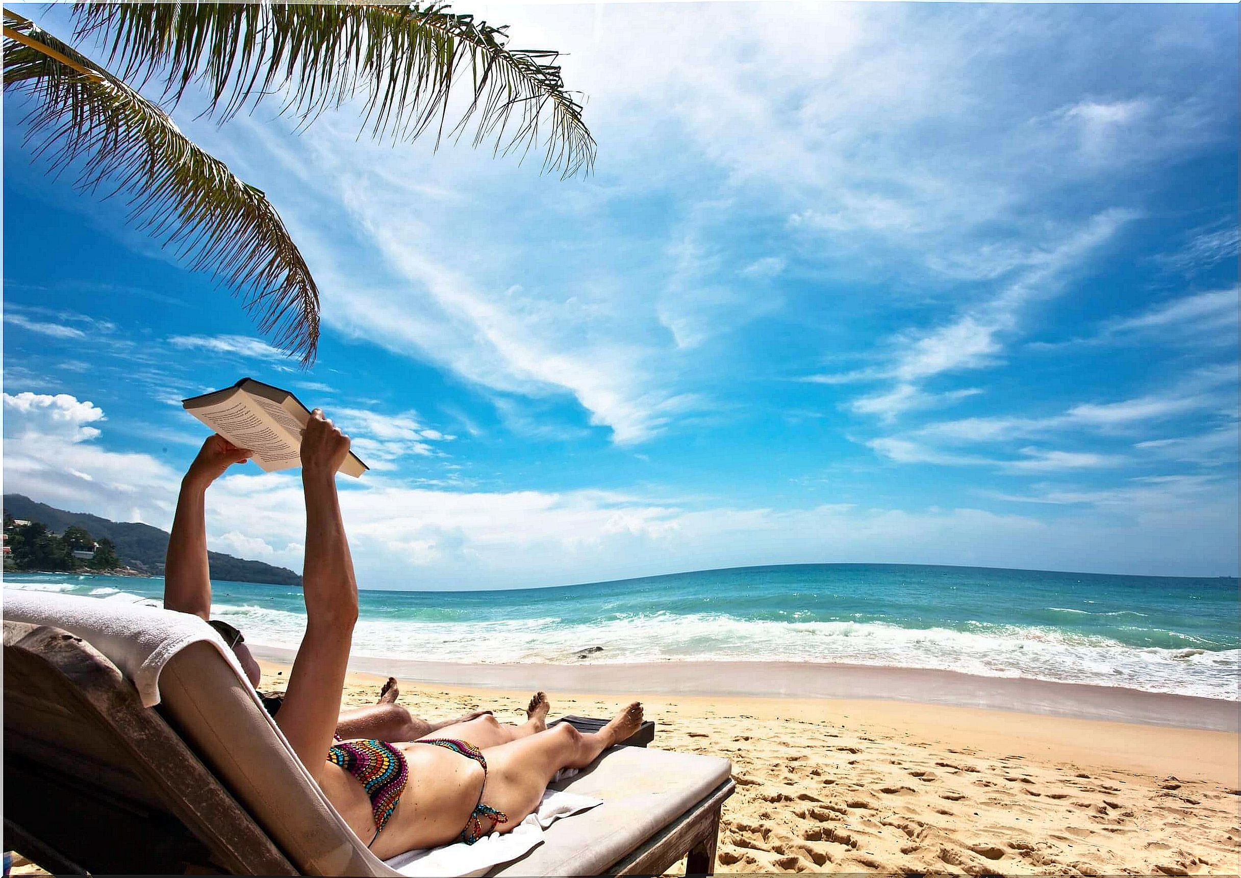 Woman on the beach reading and sunbathing.