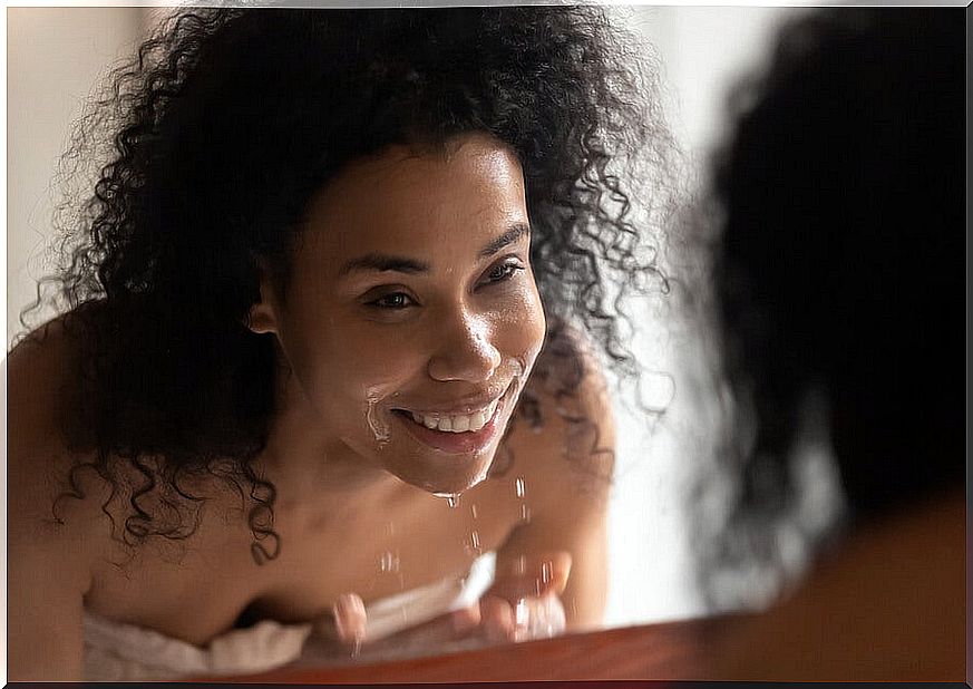 Girl looking in the mirror after washing her face.