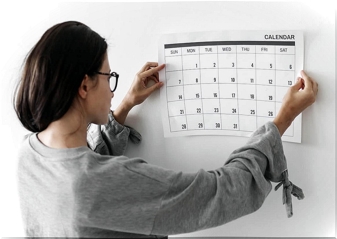 Woman hanging a calendar on the wall.