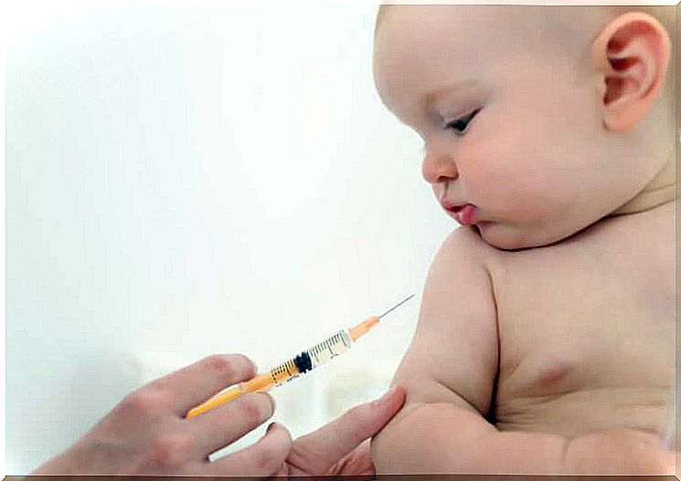 Baby watches an injection while his arm is held to be vaccinated.